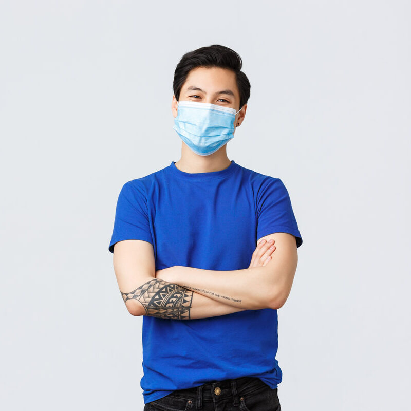 一个年轻人带着面具站着微笑。